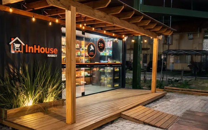 Loja InHouse Market sob pergolado de madeira em área externa, iluminada à noite